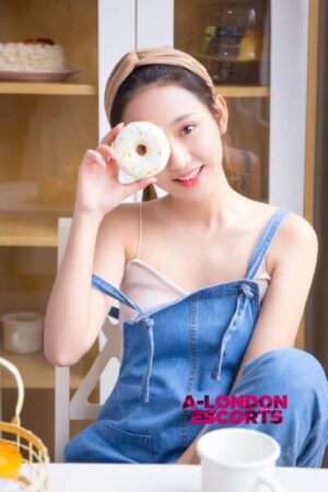 Zoe Taiwanese Mayfair Escort looks through a doughnut