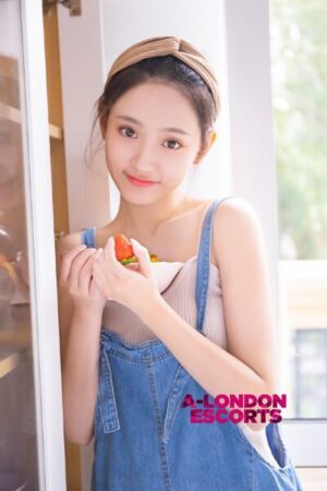 Zoe Taiwanese Mayfair Escort holding a bowl of strawberries