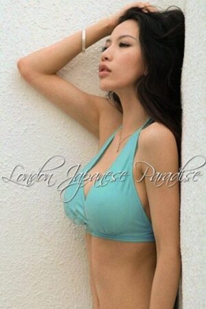 Asumi VIP Asian London Escort posing against a wall in a teal bikini