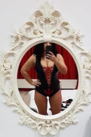 Essex escort in black corset taking selfie in mirror