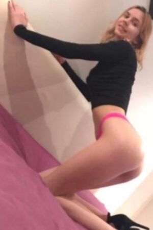 young blonde Bradford Escort kneeling on bed in pink knickers