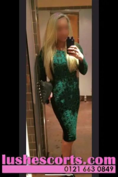 Lulu Busty Birmingham Escort in a green dress clutching a purse