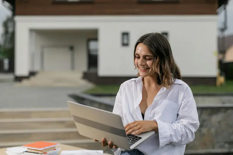 Woman using a laptop in front of her home
