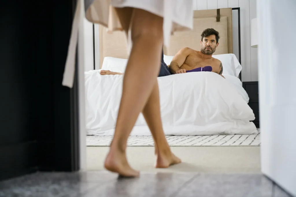Man with sex toy on the bed waiting for his partner