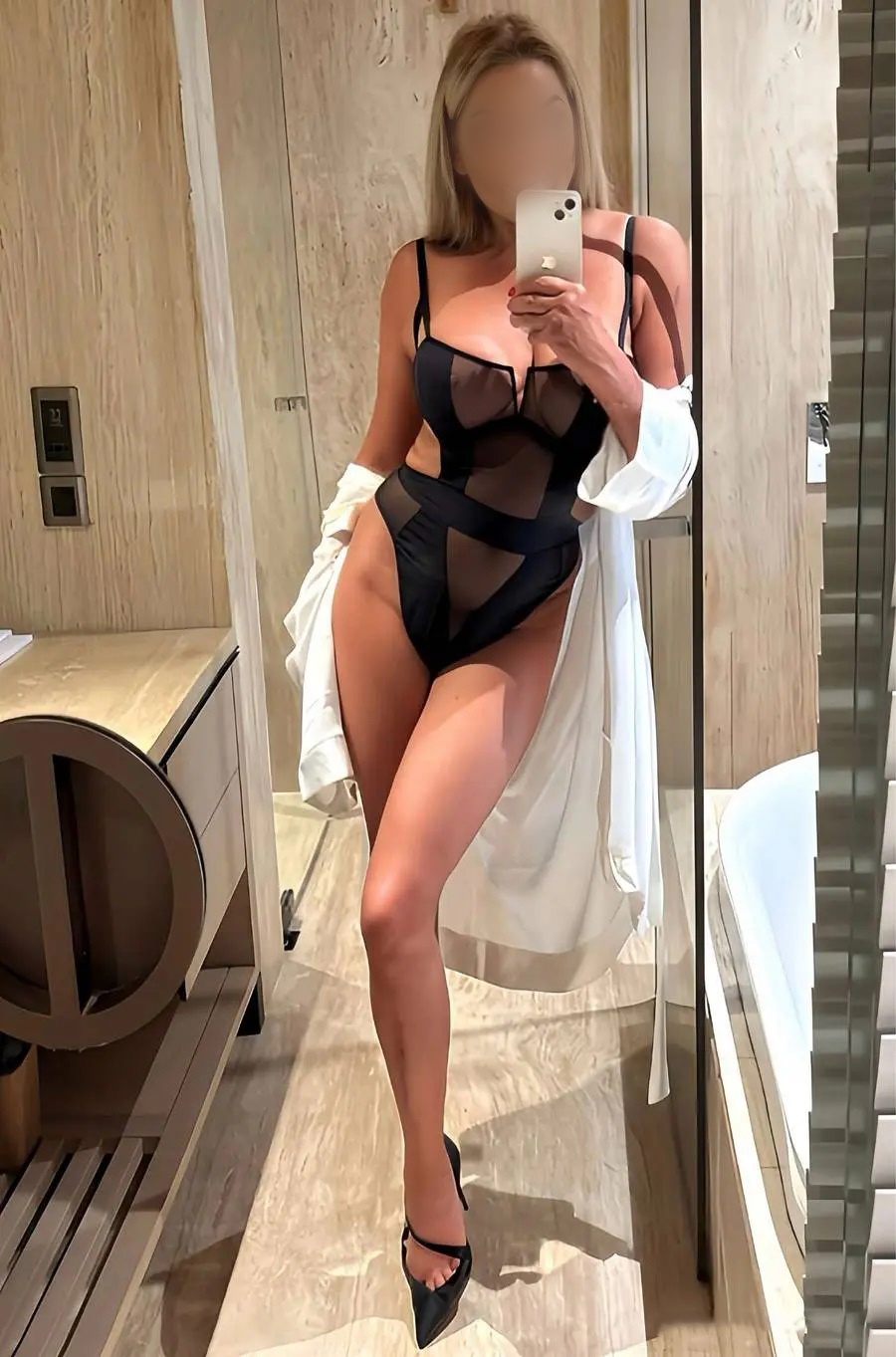Blonde escort taking a selfie in the bathroom
