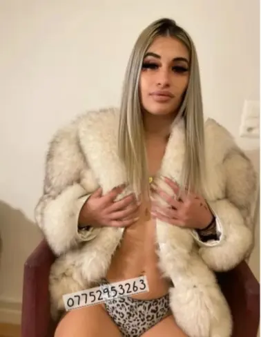 Young blonde escort topless wearing a fur coat