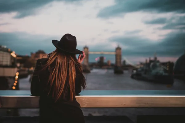 London escort wearing a black hat looking at the bridge
