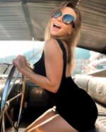 Brunette escort steering a yacht